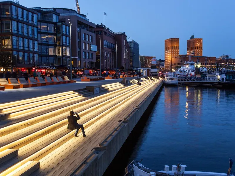 Opplyst brygge med Oslo Rådhus i bakgrunnen. Foto.