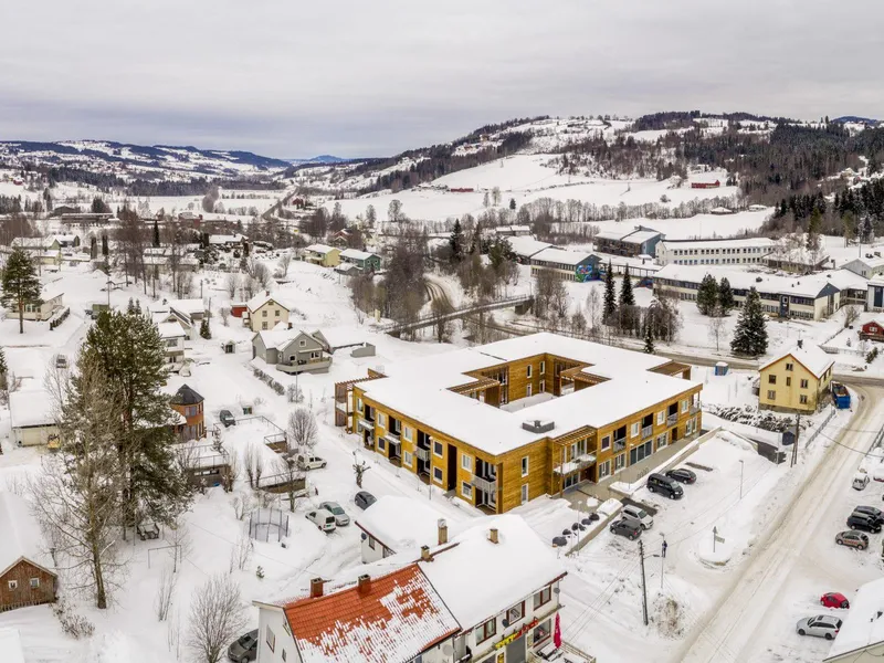 Dronefoto av et kvadratisk bygg med trefasade