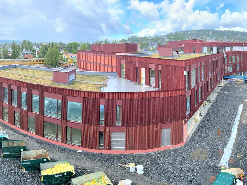 Dronefoto stort, rødt bygg, byggeplass