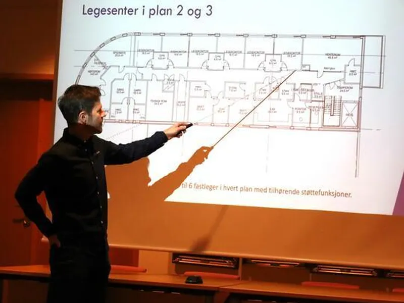 mann som står og peker på en skisse