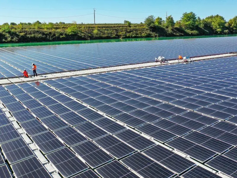 Aerial view of technicians working on a floating walkway between solar panel rows at the Saint-Élix-le-Château plant.