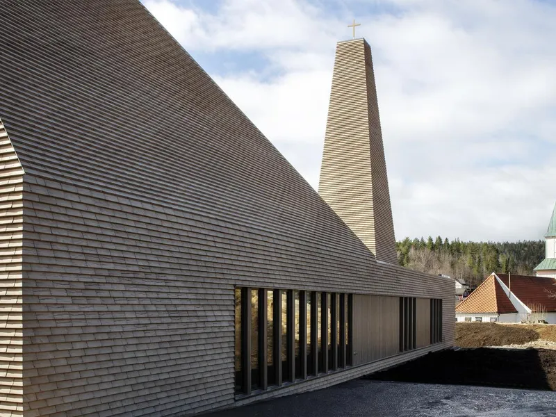 Nytt kirkebygg med gammel kirke i bakgrunnen. Foto