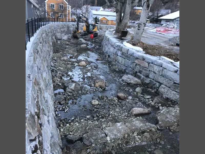 Miljøtiltak. Her bygges tersklar, for å gje jamnare vasspeil. Store steinar vert lagt ut for å gje ly og skjul for fisk, og gje varierte straumforhold for livet i elva. Foto: NVE