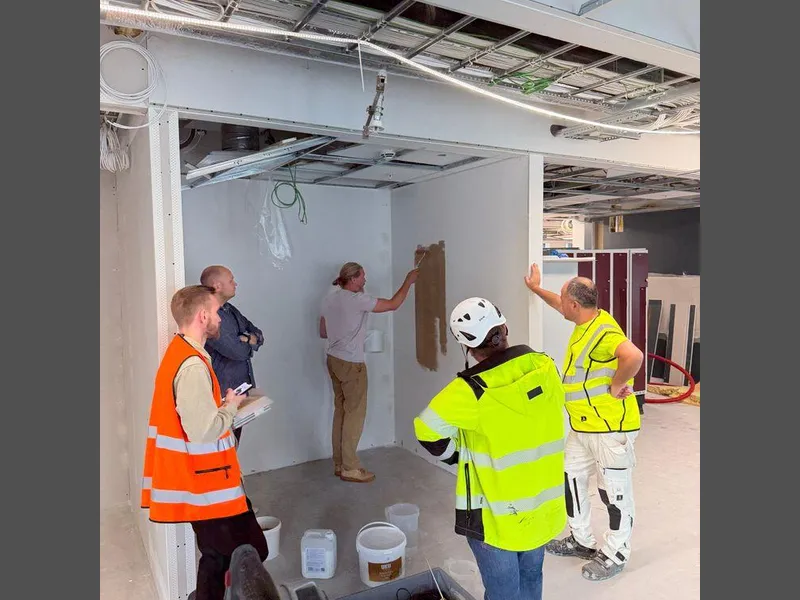 prosjektteamet følger spent med mens leiremalingen blir påført. Foto: Magna Construction Management