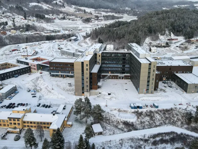 En stor bygning med mange vinduer omgitt av snø