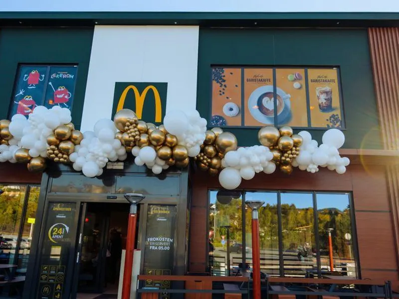 Tre personer står foran en bakgrunn med logoer fra Felleskjøpet, Norges Bygdeungdomslag, og McDonald's. Personen til venstre er en mann i dress, den midterste personen er en kvinne som holder en blomsterbukett, og personen til høyre er en mann som holder en plakat som gratulerer "Theo Sandsengen og Jørgen Andrisson Kvam" som vinnere av prisen "Årets unge bonde 2024". Alle ser mot kameraet og smiler.