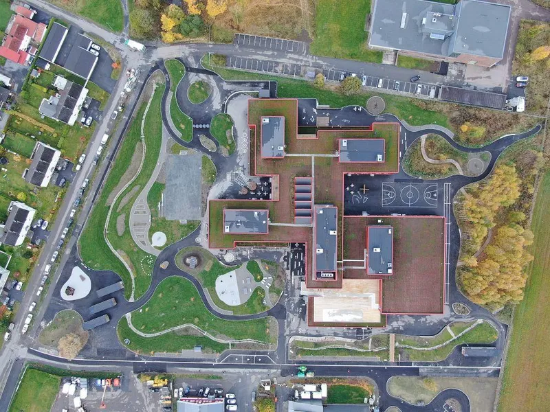 Skolebygget har en bygningskropp som en firkløver og er sentralt plassert på den 30 mål store tomten. Foto: Kruse Smith