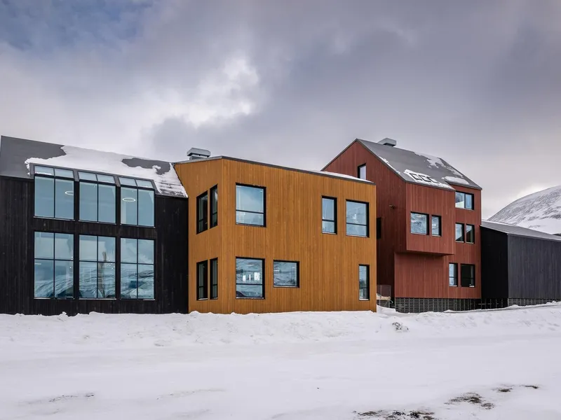 Tre hektede bygg i tre. Fasade i sort, sennepsgul og rustrød. Foto 