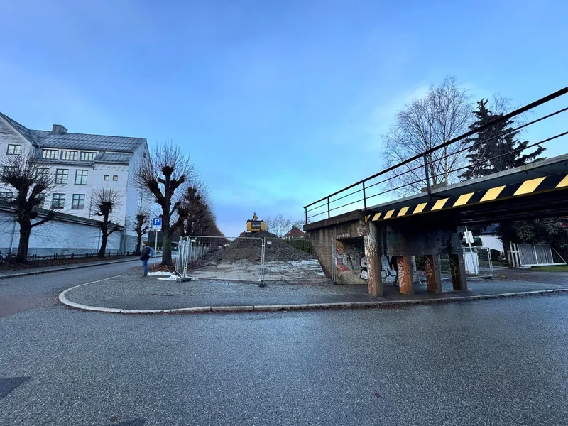Togru ved en stor grå bygning som skal rives.