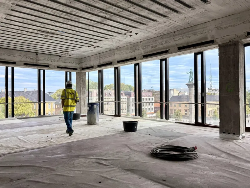 Innvendig fra et lokale ved Trondheim Torg under rehabilitering, med Asplan Viak på befaring og utsikt over Trondheim sentrum.