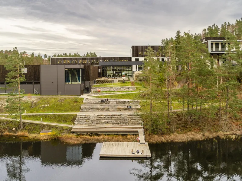 Skolebygg med amfitrapp i stein ned til flytebrygge. Foto