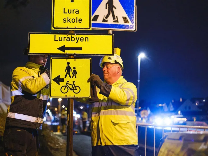 To menn henger opp veiskilt - Klikk for stort bilde
