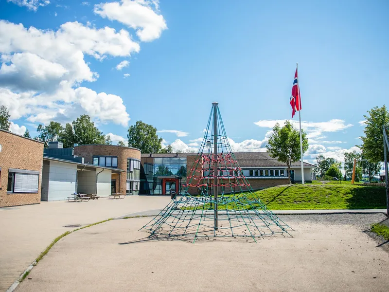 En lekeplass foran en bygning med et flagg på.