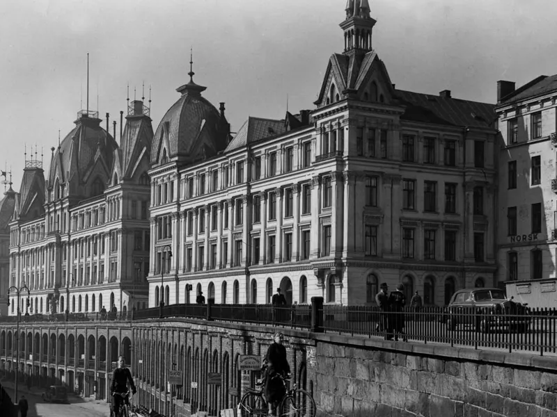 Ruseløkkbasarene og Viktoria terrasse. Folk sykler i vårsolen. Under krigen holdt tyskernes Gestapo og Sicherheitsdienst til i Victoria terrasse. I april 1946 skrev Aftenposten: 'Da det gikk mot slutten av krigen begynte tyskerne å barrikadere seg her i Oslo. Et resultat av dette var også gjenmuringen av de mange verksteds- og butikkvinduer i Ruseløkkveien under Victoria terrasse.. FOTO: NTB